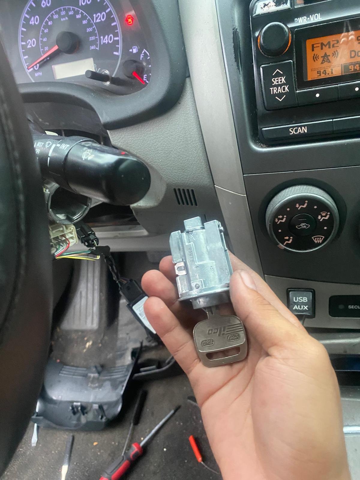 Emergency locksmith in Tampa replacing a car ignition lock cylinder and key inside a vehicle dashboard.