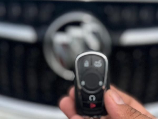 Tampa Locksmith holding a newly programmed car key fob in front of a vehicle grille during automotive key replacement service.